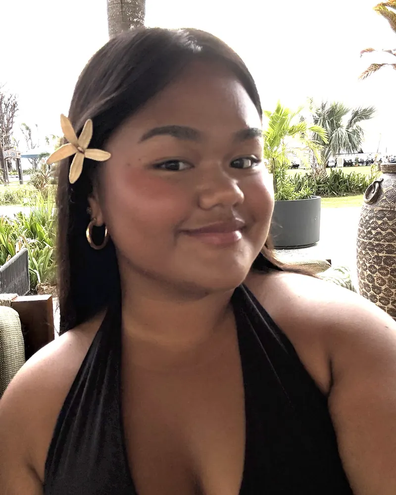 Portrait of Chelsy Reyes, smiling, with a flower in her hair
